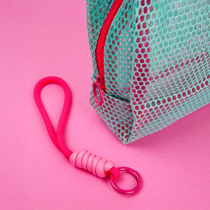 Close-up of a mint mesh Well-Kept bag with a pink zipper and a braided pink keychain on a pink background
