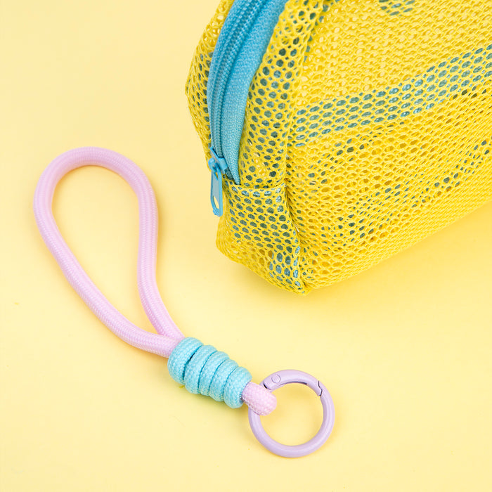 Close-up of a yellow mesh Well-Kept bag with a blue zipper and a braided pink and blue keychain on a yellow background