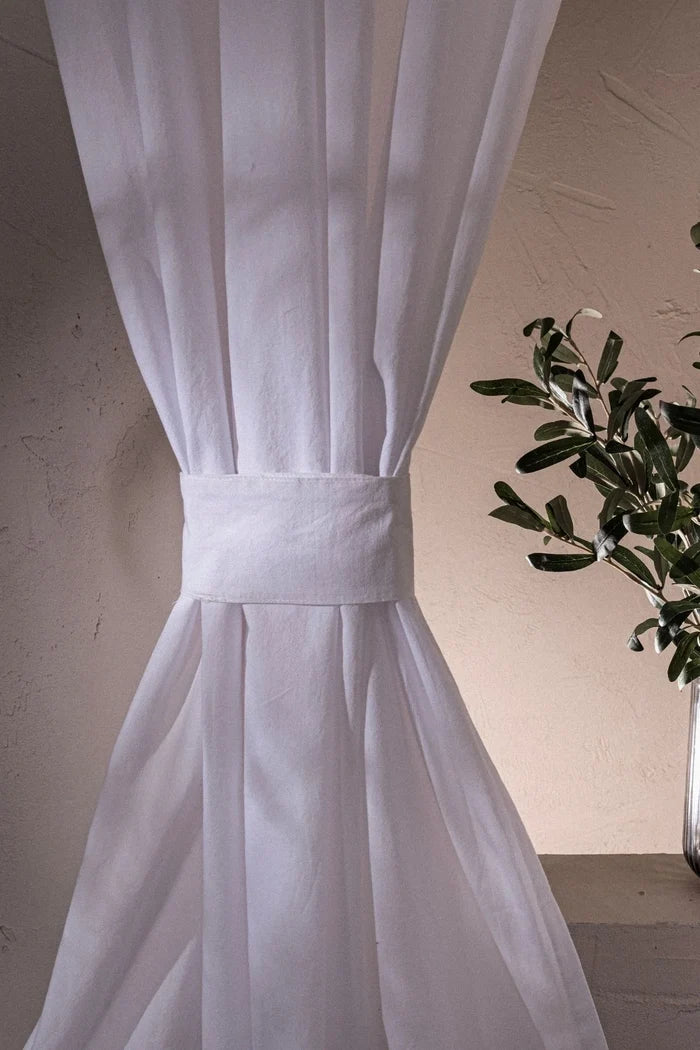 White stonewashed cotton curtain cinched with a tieback band, close-up. Handwoven in Denizli, OEKO-TEX. Vivamaison.