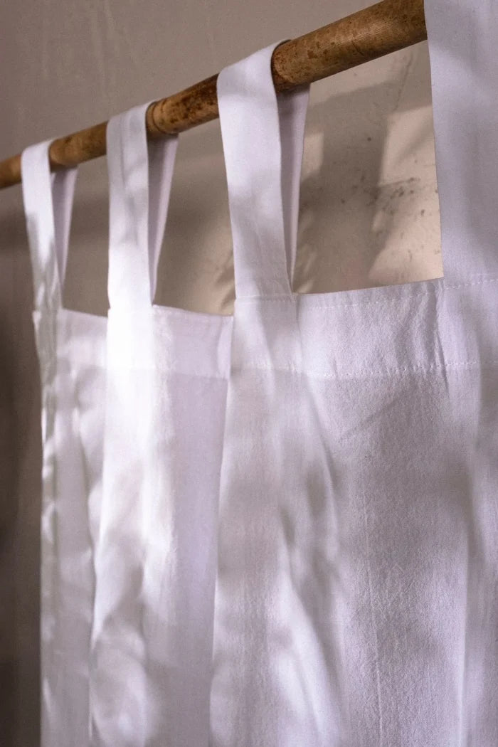 White stonewashed cotton curtain tab top loops on a bamboo rod, close-up. Handwoven in Denizli, OEKO-TEX. Vivamaison.