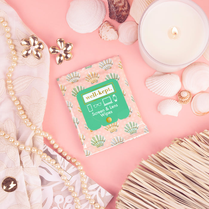 Seashell print Well-Kept screen and lens wipes pack styled on pink with pearls, seashells, and a candle